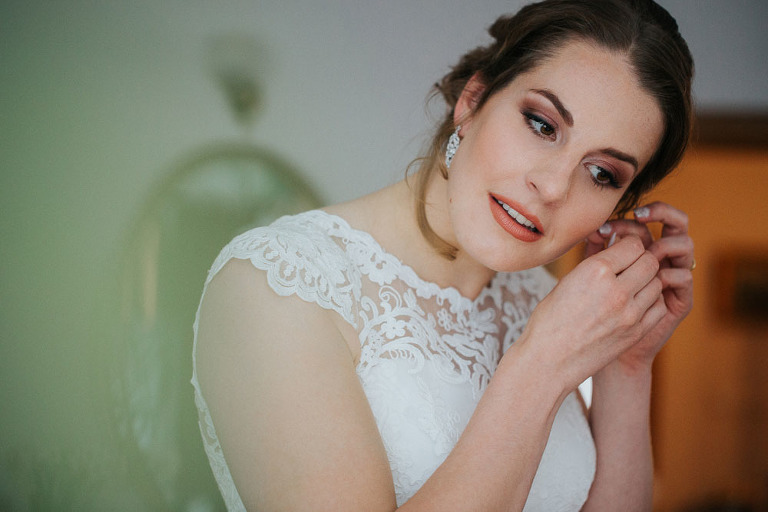 panna młoda zakłada kolczyki przed ślubem 