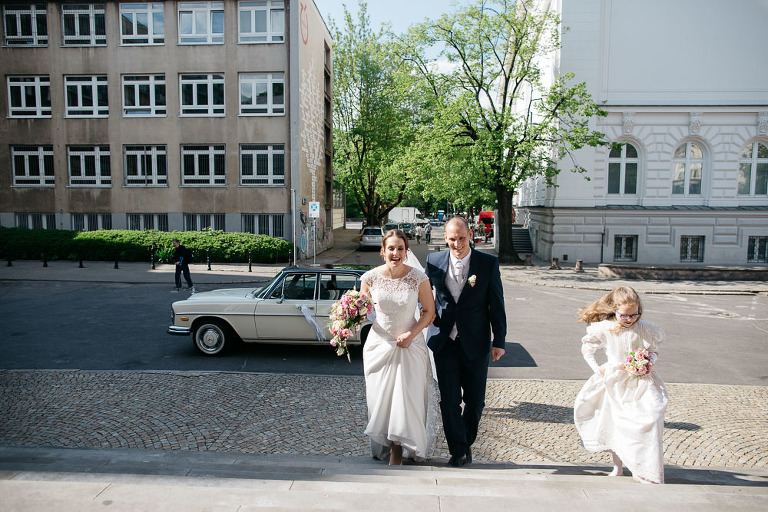 państwo młodzi wchodzą po schodach do kościoła 