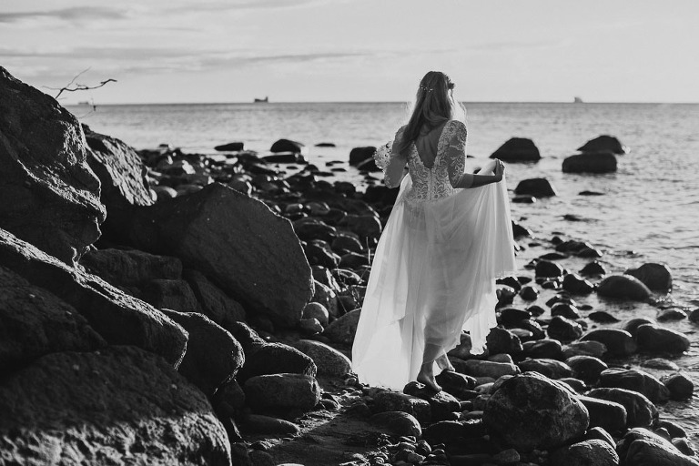 Pani młoda spacerująca po kamienistej plaży podczas sesji o wschodzie słońca 