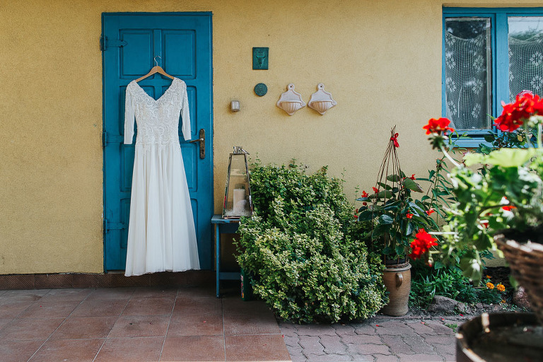 suknia Pani młodej powieszona na niebieskich drzwiach 