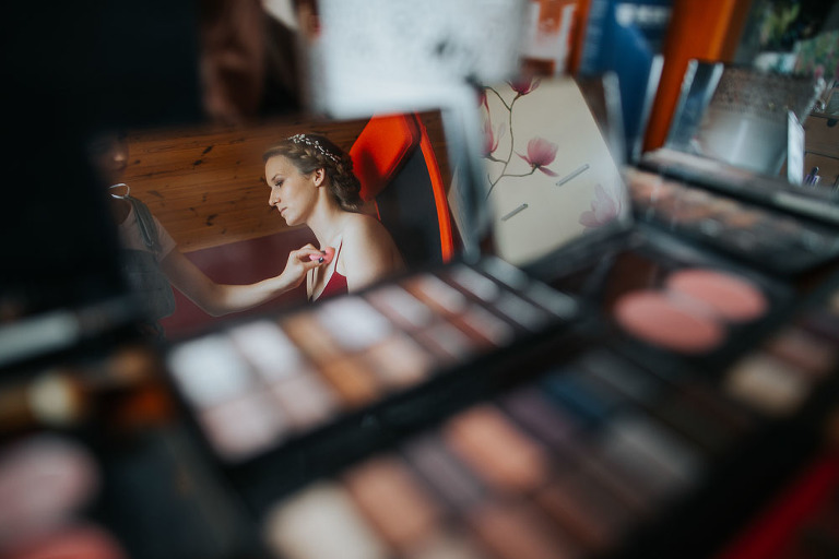 odbicie w lustrze Pani młodej w trakcie makijażu 