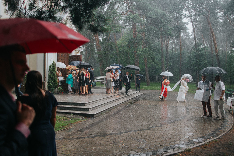 uciekająca para młoda w trakcie deszczu na ślubie 