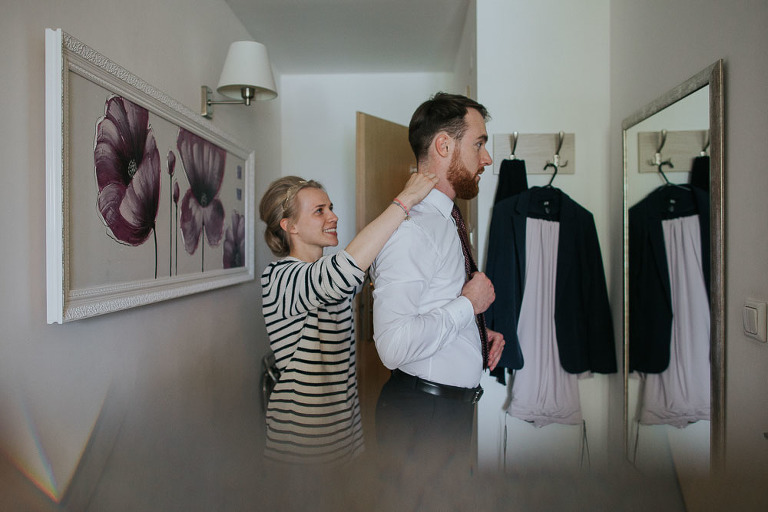 pani młoda pomaga narzeczonemu założyć krawat 