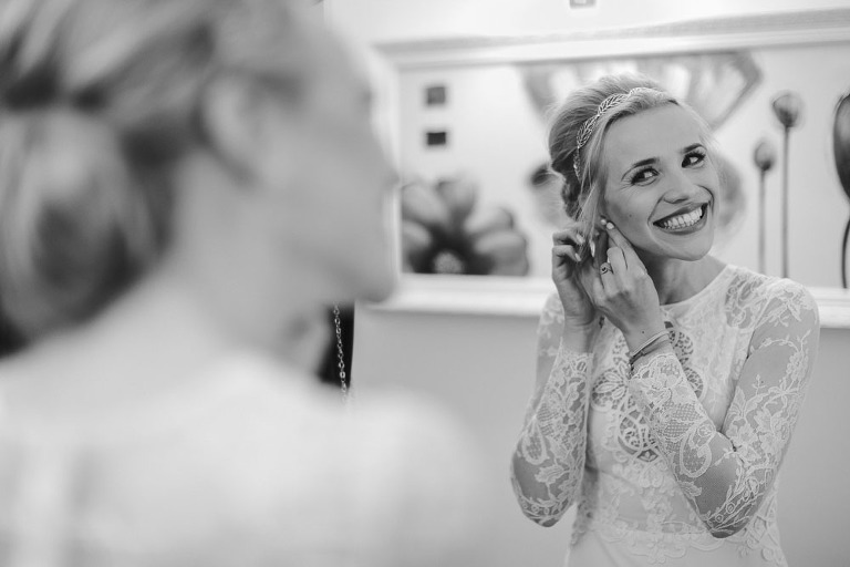 uśmiechnięta pani młoda zakłada kolczyk 