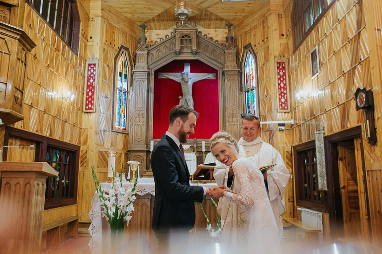 roześmiana panna młoda podczas ślubu w małym drewnianym kościółku