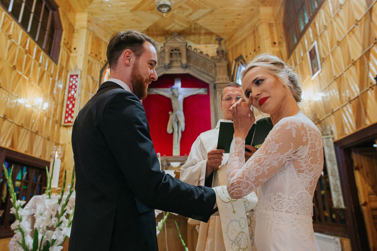 wzruszona panna młoda podczas ślubu w małym drewnianym kościółku