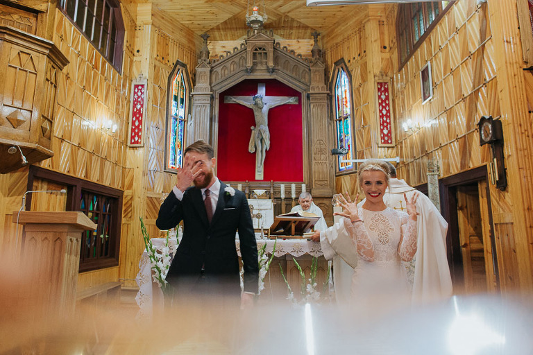 szczęśliwi nowożeńcy w małym drewnianym kościele