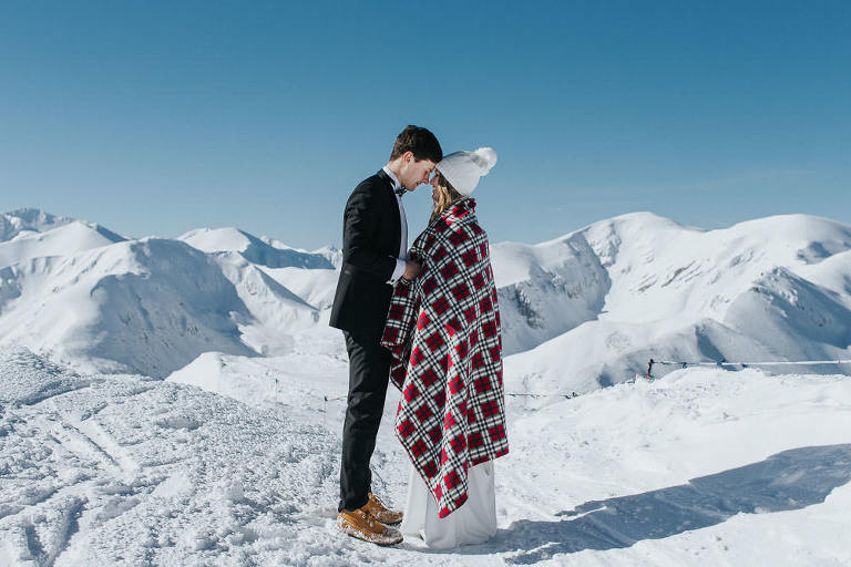 zimowa sesja ślubna w górach para otulona czerwonym kocem 