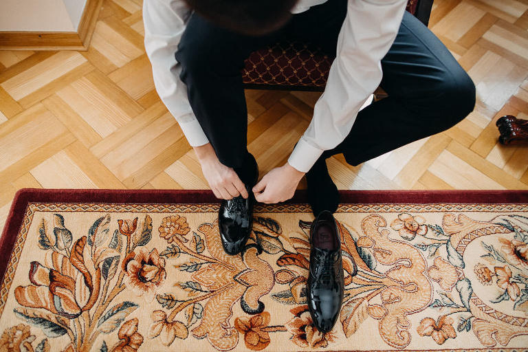 Pan młody wiąże buta przed zimowym ślubem 