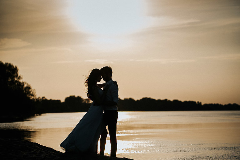 przytulona para nowożeńców na tle zachodu słońca