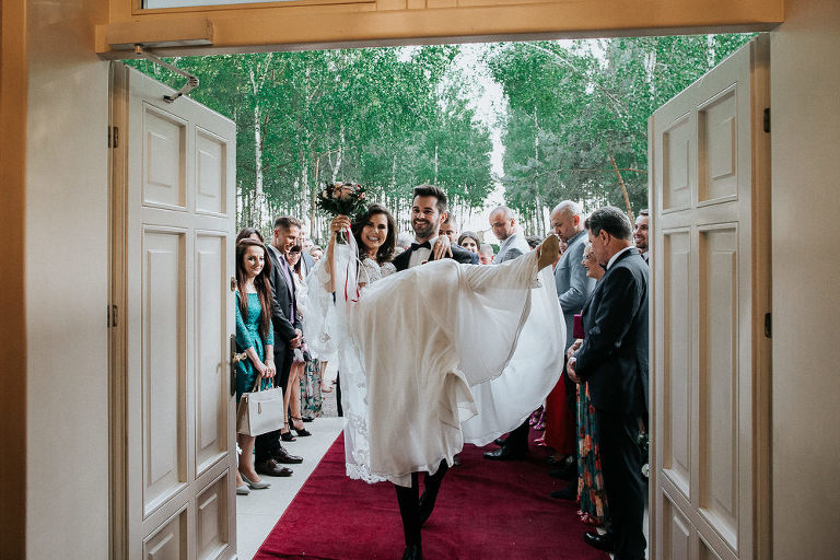 pan młody przenosi przez próg swoją żonę na weselu w Złotopolska dolina 