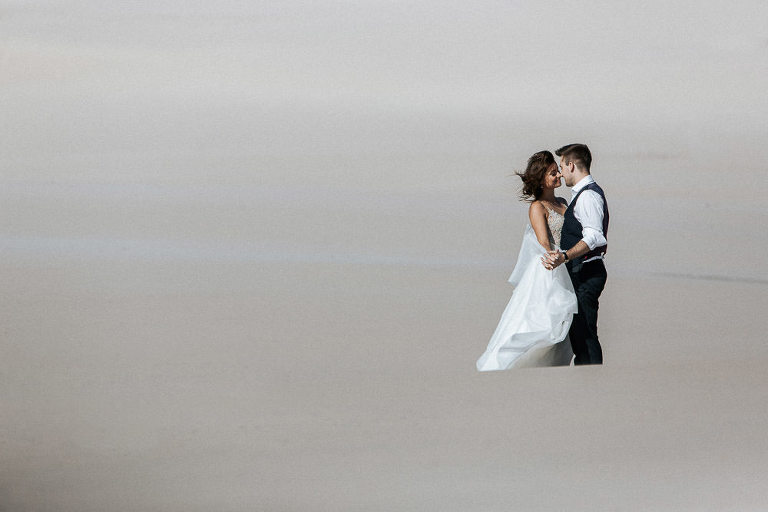 para stojąca na pustyni sesja ślubna na wydmach w Łebie