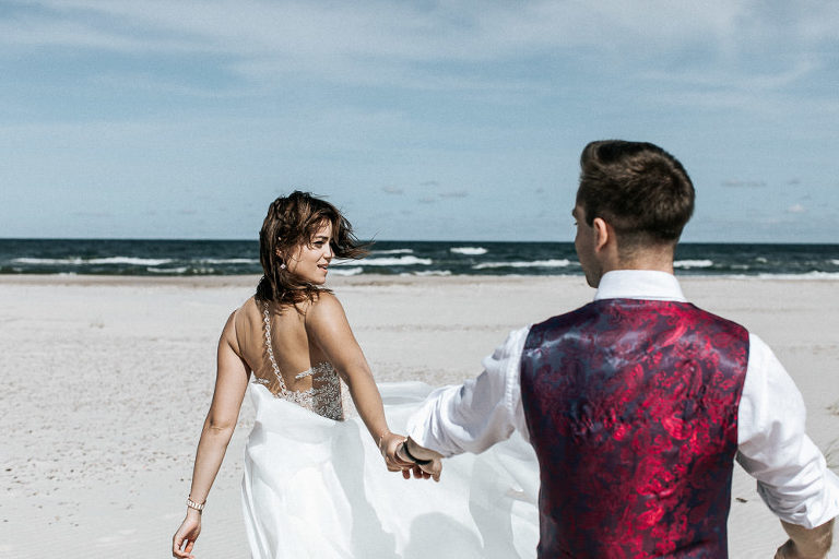 para trzymająca się za ręce podczas spaceru po plaży nad morzem 