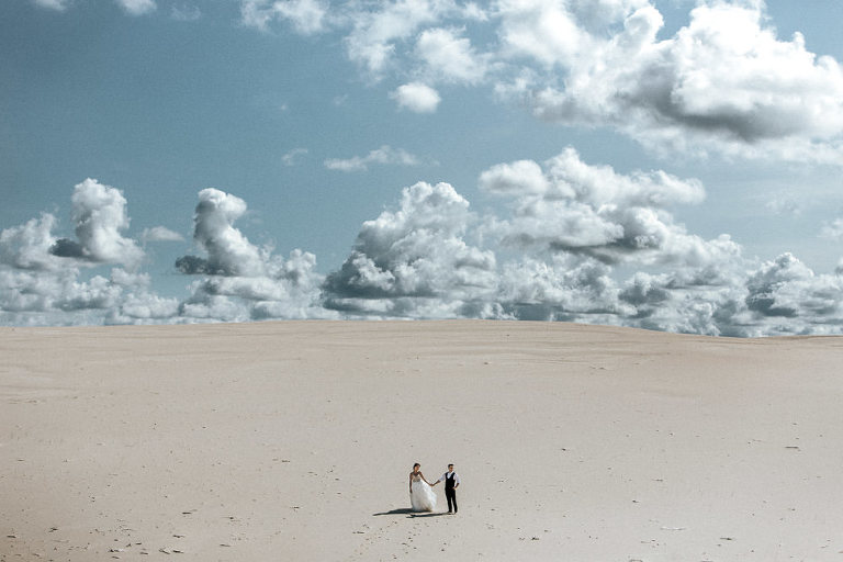 para stojąca na dużej pustyni podczas sesji ślubnej w Łebie