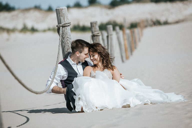 para siedząca na piasku podczas sesji ślubnej w słowiński parku narodowym 