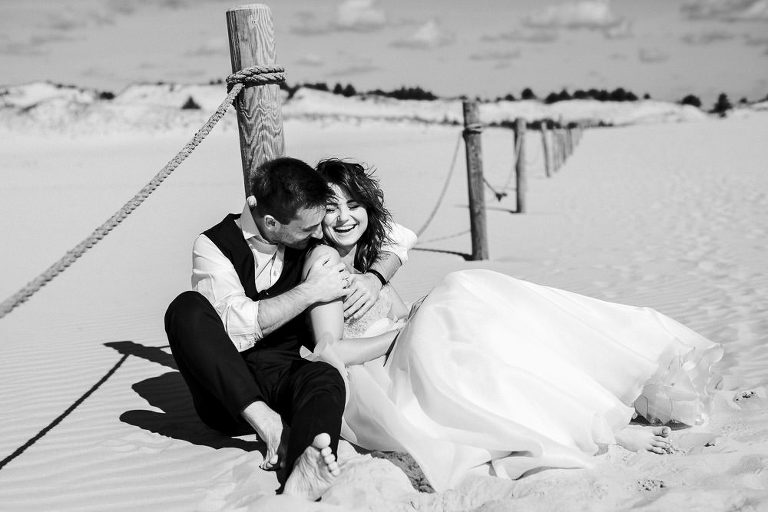 siedzący nowożeńcy na piasku podczas pleneru na wydmach w Łebie