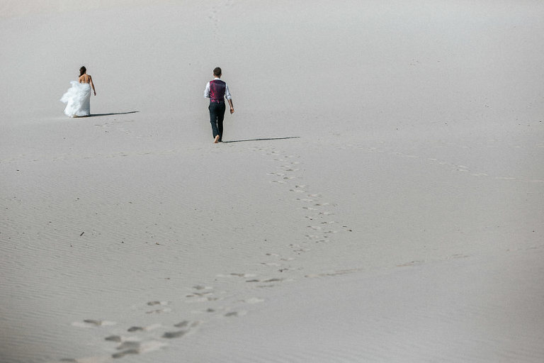spacerujący nowożeńcy po plaży w trakcie sesji na wydmach w Łebie