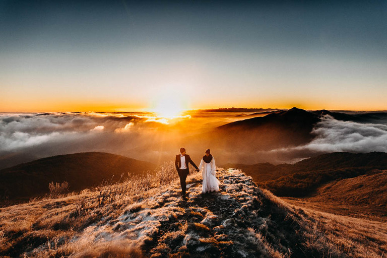 sesja zdjęciowa w Bieszczadach idącej pary ślubnej na tle wschodzącego słońca 