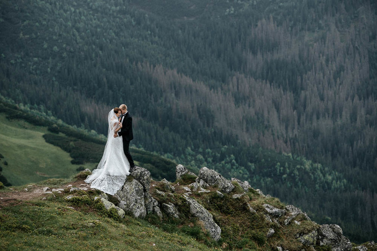 para ślubna stojąca w trakcie sesji zdjęciowej na skałach w tle zielone Bieszczady 