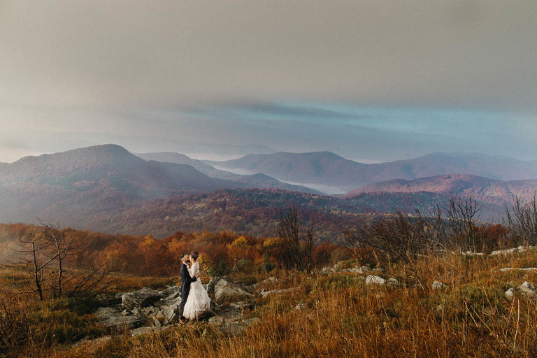 Sesja plenerowa w Bieszczadach jesienią para ślubna stojąca na tle kolorowych drzew 